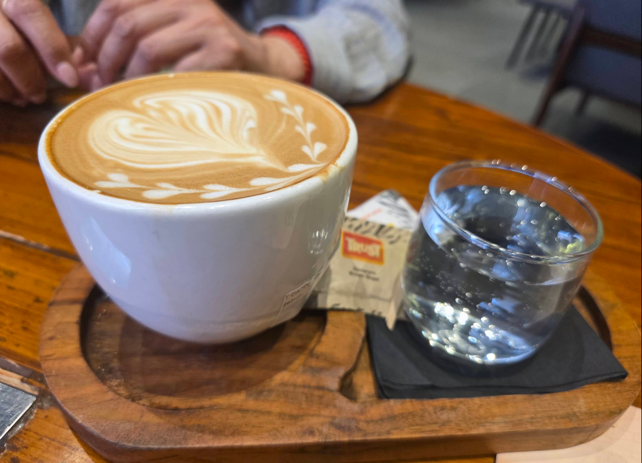 Latte with elaborate art on a wooden tray