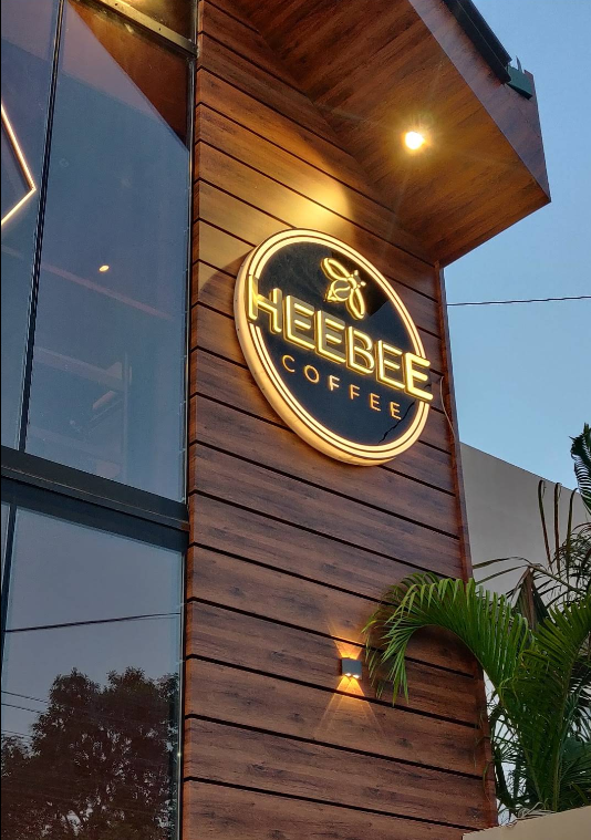 HeeBee Coffee neon signage on a wood facade